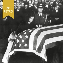 Jaqueline Kennedy, die Witwe des ermordeten US-Präsidenten John F. Kennedy, betet mit ihrer Tochter Caroline (l) am mit der US-Flagge bedeckten Sarg ihres Gatten im Weißen Haus in Washington am 25.11.1963.  | Bild: picture-alliance / dpa | UPI