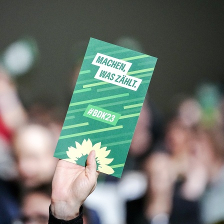 Eine Karte der Grünen mit dem Slogan "Machen, was zählt" wird hochgehalten