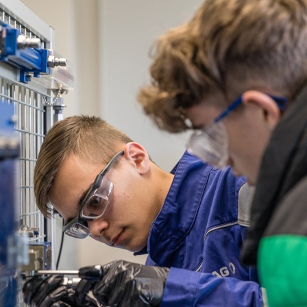 Marvin Walker (l), Mechantroniker im dritten Ausbildungsjahr, zeigt im Hydraulikkabinett Hugo Seidel an einer Versuchswand Aufgaben aus seiner Ausbildung