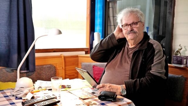 Der 73-jährige Wolfram Mielke sitzt am Esszimmertisch und hält ein Tablet in der Hand