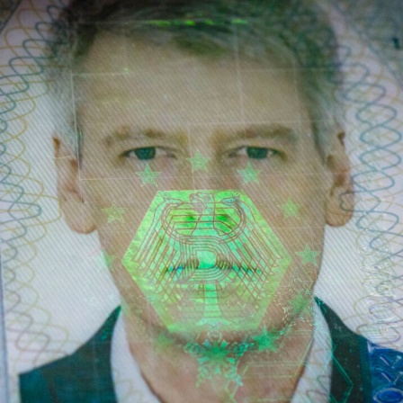 Auf dem biometrischen Passfoto eines Reisepasses spiegelt sich ein Bundesadler als Hologramm (Bild: picture alliance/photothek/Thomas Trutschel)