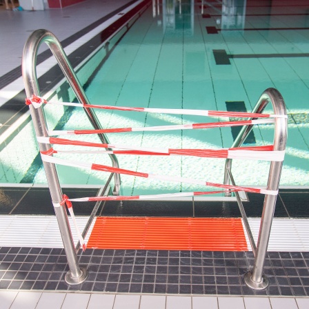 Die Leiter zu einem Schwimmbecken ist mit rot-weissem Trassenband abgesperrt