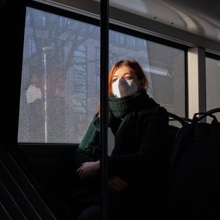 Eine junge Frau trägt eine FFP2-Maske im Bus.