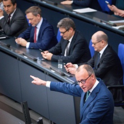 CDU-Politiker Friedrich Merz hält im Bundestag eine Rede, mit Bundeskanzler Olaf Scholz, Bundeswirtschaftsminister Robert Habeck und Finanzminister Christian Lindner im Hintergrund.