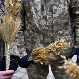 Ukrainische Soldaten halten kleine Sträuße aus Hafer und Roggen in den Händen.