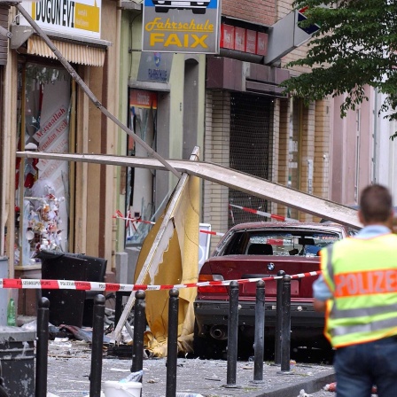 Ein Polizist sichert in Köln die Spuren einer Explosion in einer Wohnstraße.