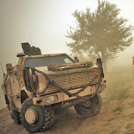 Ein Soldat winkt ein gepanzertes Fahrzeug zu sich heran.