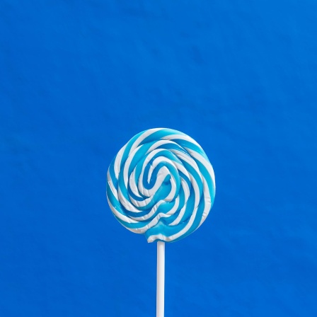 Ein blau-weißer Lutscher am Stil vor blauem Hintergrund.