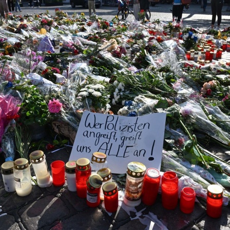 Blumen und Kerzen liegen auf dem Marktplatz in Mannheim