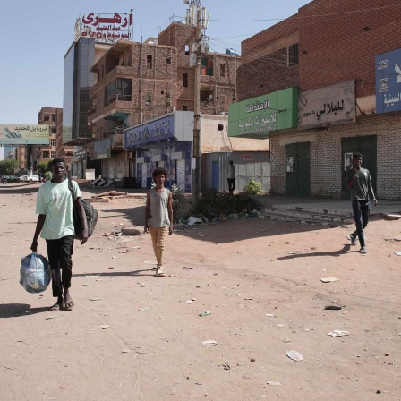 Menschen in der sudanesischen Hauptstadt Khartum gehen an verschlossenen Geschäften vorbei. (Bild: picture alliance/dpa/AP)