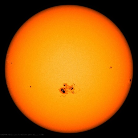 Auf einem Bild der Sonne sind dunkelorangene bis schwarze Flecken zu sehen.