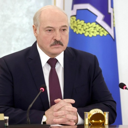 Alexander Lukaschenko sitzt vor zwei Mikrofonen.