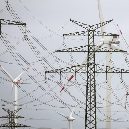 Windräder sind hinter Strommasten am Umspannwerk Heide West zu sehen