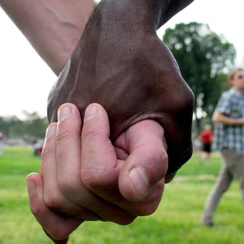 Zwei Teilnehmer einer Demonstration gegen Rassismus halten sich an den Händen