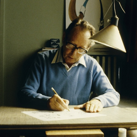 Der Comicbuch-Zeichner Maurice De Bevere alias "Morris" sitzt an einem Schreibtisch.