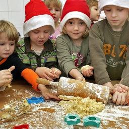 In einem Kindergarten backen Kinder Weihnachtsplätzchen. 