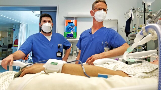 Zwei Ärzte in Atemschutzmaske stehen am Bett eines Beatmungspatienten
