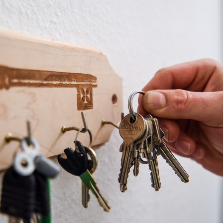 Ein Mann hängt einen Schlüsselbund an einen Haken am Schlüsselbrett