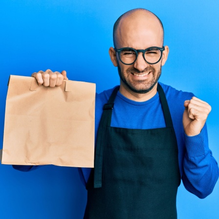 Euphorischer Kellner mit einer Mitnehm-Tüte in der Hand
