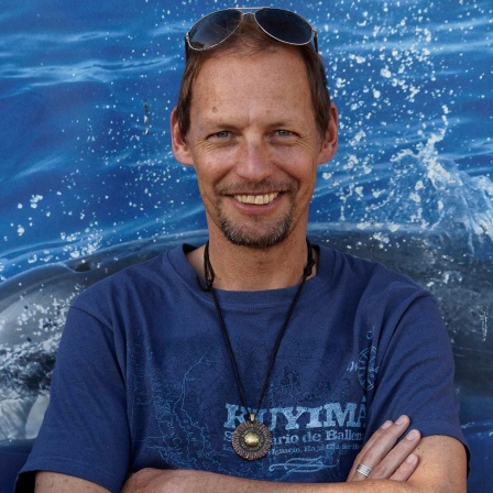 Fabian Ritter hält die Arme verschränkt und lächelt in die Kamera. Er trägt ein blaues T-Shirt und eine in die kurzen braunen Haare geschobene Sonnenbrille.