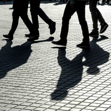 Schatten von Passanten die über eine Straße laufen.