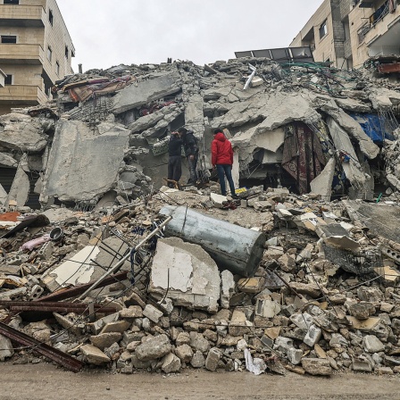 Menschen betrachten die Trümmer eines zerstörten Wohnhauses im syrischen Idlib.