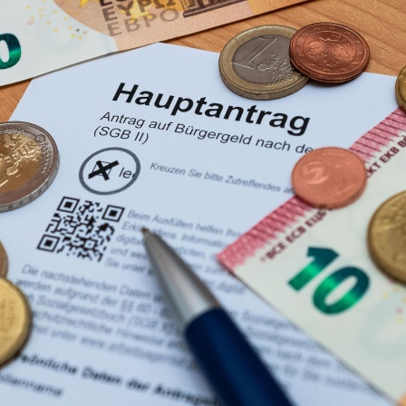 Euroscheine und -münzen liegen um einen Antrag auf Bürgergeld verteilt (Bild: picture alliance / Zoonar)