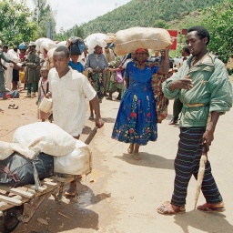 12. April 1994: Angehörige der Hutu fliehen südlich von Kigali vor den schweren Kämpfen zwischen den Regierungstruppen der Hutu und den Rebellen der Rwanda Patriotic Front (RPF) der Tutsi. Der Mann rechts ist Zivilist, Hutu und arbeitet auf der Seite der Regierungstruppen. Er kontrolliert die Flüchtlinge um sicherzustellen, dass keine Tutsi darunter sind. Hunderttausende Menschen fliehen nach dem Mord am Präsidenten Ruandas am 6. April 1994 vor den Massakern in Kagali und Umgebung.