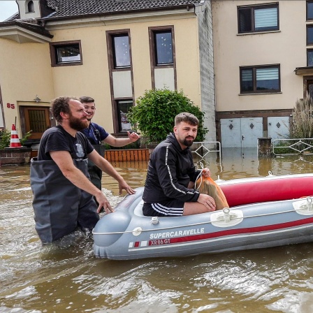 Einsatzkräfte der Freiwilligen Feuerwehr transportieren einen Mann mit einem Schlauchboot