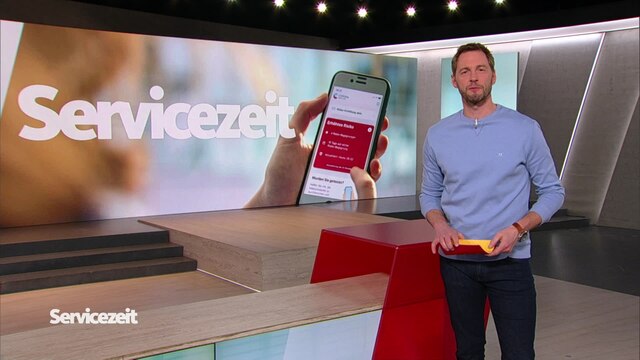 Der Moderator Dieter Könnes im SZ Studio vor einem  Smartphone mit der geöffneten Corona-Warn_App