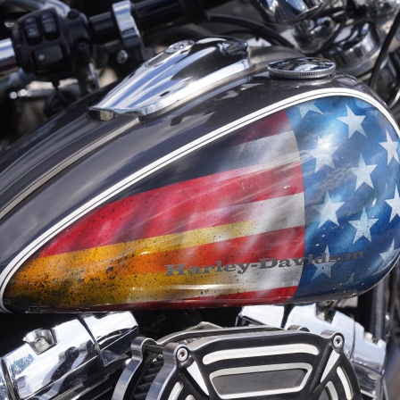 Der Tank eines Harley-Davidson-Motorrads ist mit einer US- und einer deutschen Flagge bemalt, die ineinander übergehen.