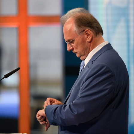 Reiner Haseloff (CDU), Ministerpräsident von Sachsen-Anhalt, schaut am Abend der Landtagswahl auf seine Uhr.