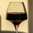 Ein Rotweinglas, im Hintergrund Schatten des Glases und einer Flasche