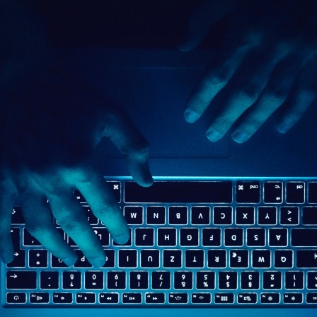 Hände tippen etwas auf einer Computertastatur.