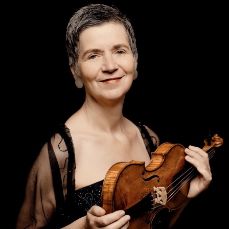 Die Geigerin Petra Müllejans, lächelnde Frau mit kurzen, dunkelgrauen Haaren -- in der Hand eine Geige