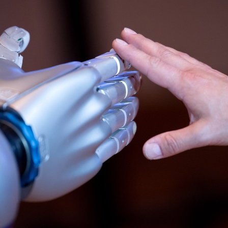 Die Hand eines Menschen berührt die Hand eines Roboters.