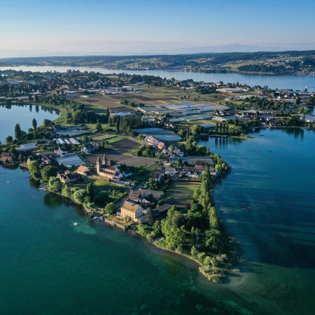 Die aufgehende Sonne strahlt die romanische Säulenbasilika, St. Peter und Paul, auf der Insel Reichenau an. Aufnahme mit Drohne.