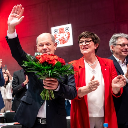 Bundeskanzler Olaf Scholz bei der Bestaetigung als Kanzlerkandidat der SPD winkend mit Blumenstrauss beim ausserordentlichen SPD Bundesparteitag in Berlin gemeinsam mit Saskia Esken Bundesvorsitzende und Lars Klingbeil Bundesvorsitzender