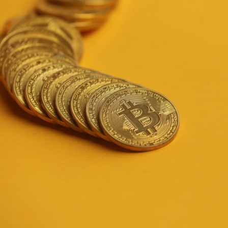 Fotoillustration zeigt die Kryptowährung Bitcoin auf gelbem Hintergrund.