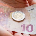 Eine Person hält einen 10 Euro Schein und eine 2 Euro Münze in der Hand, Symbolbild Erhöhung gesetzlicher Mindestlohn