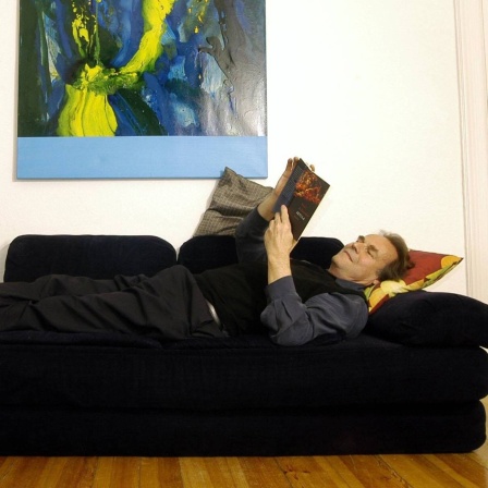 Das Beitragsbild des WDR3 Kulturfeature "Zwischen Musik und Politik" zeigt den Schriftsteller Peter Schneider auf einem Sofa liegend in seiner Wohnung in Berlin, 2005.