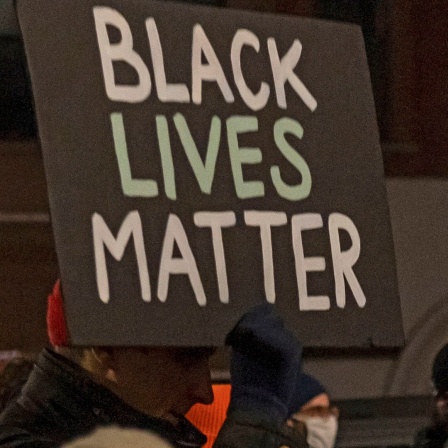 Ein Demonstrant hält ein Schild mit der Aufschrift "Black Lives Matter" während eines Protestmarsches in Brooklyn gegen den Freispruch von Kyle R. hoch.