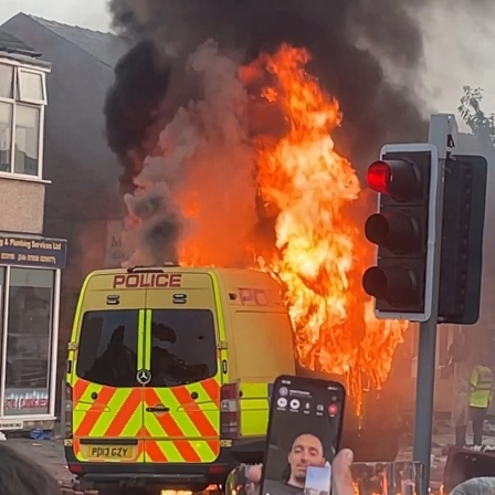 Ein Fahrzeug der Polizei brennt während Unruhen in Southport.