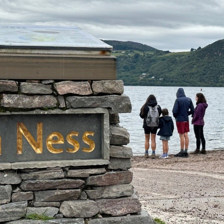 Menschen stehen am Ufer des Sees Loch Ness in Schottland 