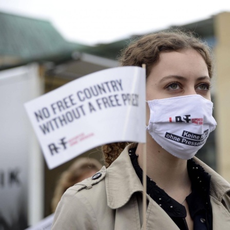 Eine junge Frau trägt Berlin bei einer Aktion von Reporter ohne Grenzen einen Mundschutz auf dem "Keine Freiheit ohne Pressefreiheit" gedruckt steht. 