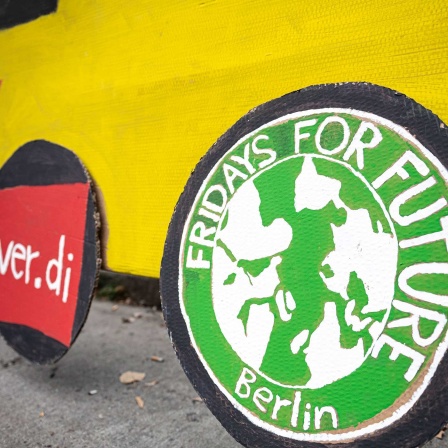 Aktivisten von Fridays for Future unterstützen vor dem BVG Betriebshof Cicerostraße die Streikenden mit Plakaten und einem gelben Bus aus Pappe, auf den selbstgemalte Logos von Verdi und Fridays For Future geklebt. 