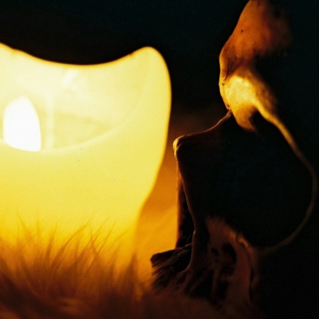 Ein Totenkopf wird durch das Licht einer Kerze angestrahlt.