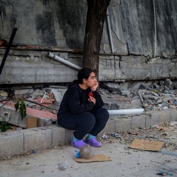 Frau vor zusammengestürztem Haus nach dem Erdbeben in der Türkei
