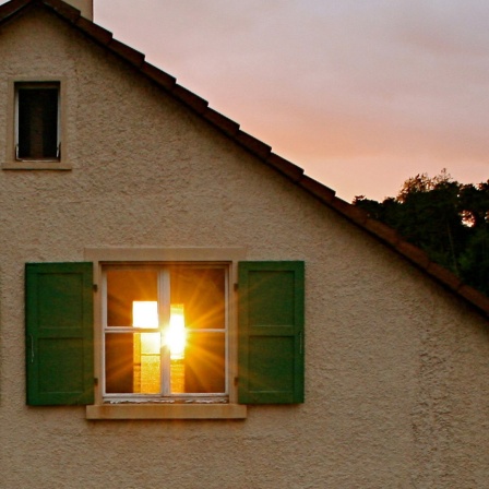 Die Sonne scheint durch ein geöffnetes Fenster in einem alten Haus. 