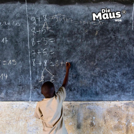 Ein Schüler steht in Burundi an der Tafel und löst Matheaufgaben.